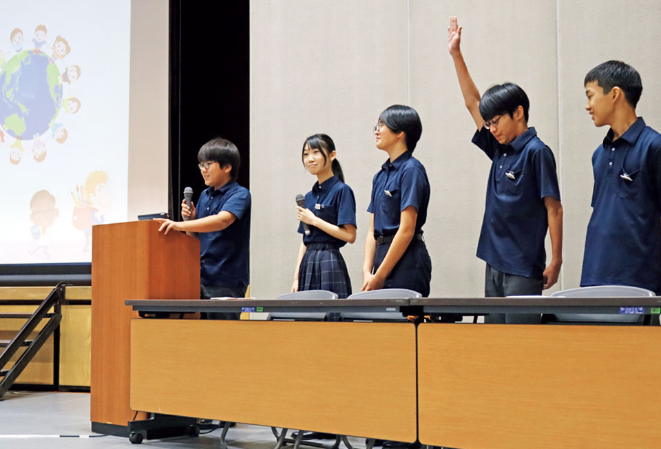 スクリーンを使って壇上で発表している生徒たち