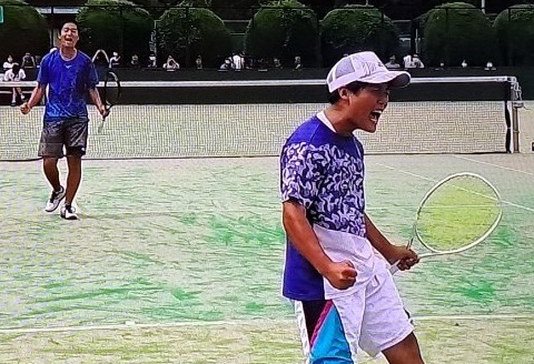 テニスコート上でガッツポーズをする生徒
