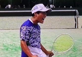 テニスコート上でガッツポーズをする生徒
